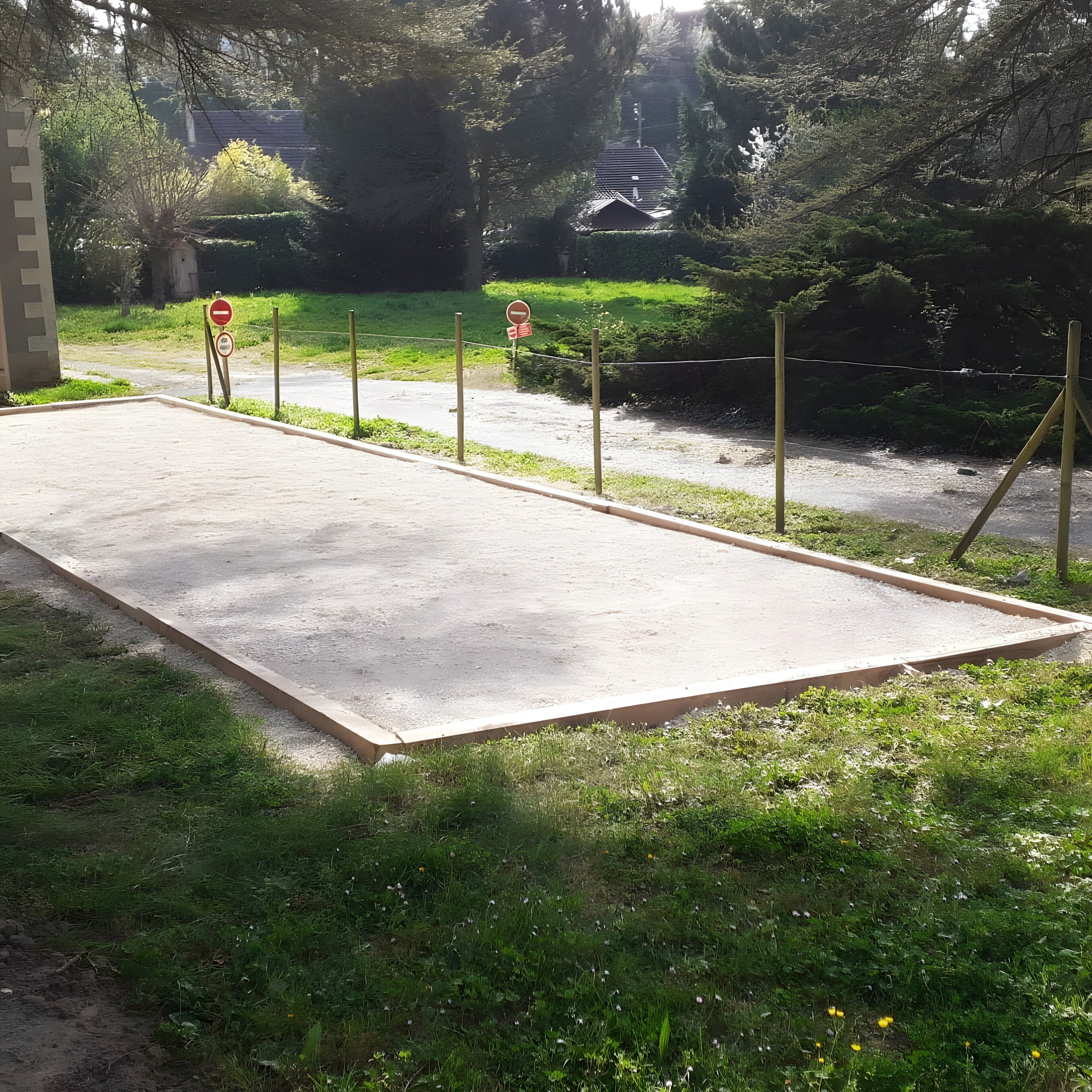 Una piattaforma in cemento con un segnale di divieto di accesso, circondata da vegetazione e zona residenziale.