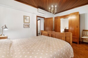 Een slaapkamer met een bed, een houten kledingkast, een spiegel en een kroonluchter.