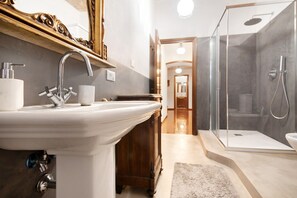 Een badkamer met een wastafel, spiegel, douche en een houten kast.