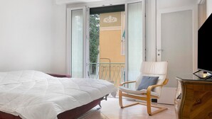 Une chambre à coucher avec un lit, une chaise, une commode et un balcon offrant une vue.