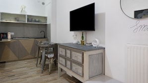 A modern kitchen with a built-in stove, a dining area with a table and chairs, and a large flat-screen TV mounted on the wall. - Apartment 'Lally's Nest' with Private Terrace, Wi-Fi and Air Conditioning (Rapallo)