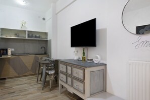 A modern kitchen with a built-in stove, a dining area with a table and chairs, and a large flat-screen TV mounted on the wall. - Apartment 'Lally's Nest' with Private Terrace, Wi-Fi and Air Conditioning (Rapallo)