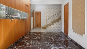 A hallway with wooden cabinets, a marble floor, a staircase with patterned railings, and a patterned wall. - Apartment 'Lally's Nest' with Private Terrace, Wi-Fi and Air Conditioning (Rapallo)