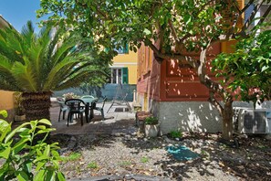 Un espace patio aménagé avec du mobilier d’extérieur, un palmier et un bâtiment aux murs jaunes et rouges.