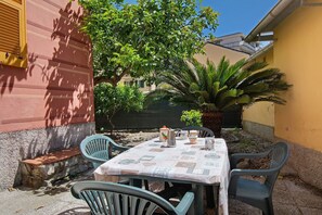 Une terrasse avec une table dressée pour deux personnes, entourée de chaises, et une plante en pot.