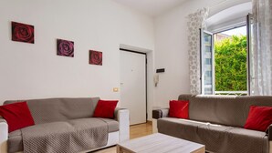 Una sala de estar con dos sofás, una mesa de centro y una puerta que da a un balcón.