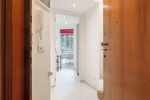 A hallway with a wooden door, a telephone, and a window with a red blind. - Apartment 'Margherita - Seafront' with Balcony, Wi-Fi and Air Conditioning (Rapallo)