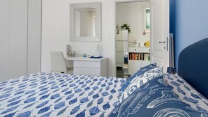 Ein Schlafzimmer mit Bett, Schreibtisch, Stuhl, Spiegel und Bücherregal.