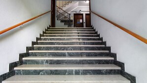 Eine Marmortreppe mit hölzernen Geländern, die zu einer Tür mit einem Schild führt.
