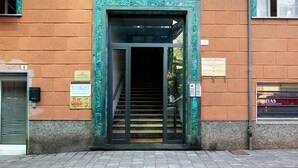 Ein Gebäudeeingang mit Glastür, einer Treppe und einem Schild mit der Aufschrift 'INTERGEST'.