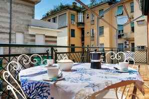 A round table with a floral tablecloth, white chairs, and a metal railing. - Apartment 'Gaia' with Wi-Fi and Air Conditioning (Rapallo)