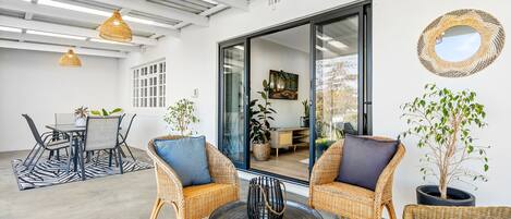A spacious patio with wicker furniture, a dining area, and a large sliding glass door leading to an indoor space.