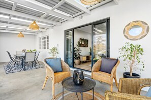 A spacious patio with wicker furniture, a dining area, and a large sliding glass door leading to an indoor space. - Winelands Getaway (Stellenbosch)
