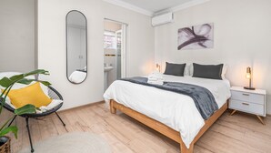 A bedroom with a bed, bedside table, mirror, and a chair. - Winelands Getaway (Stellenbosch)
