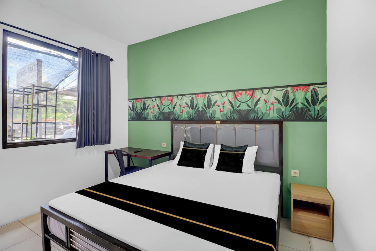Une chambre d’hôtel avec un lit, un bureau et une fenêtre avec des rideaux.