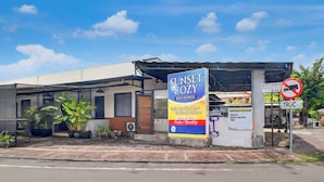 A building with a sign for 'Sunset Cozy Residence' advertising room for rent. - Hotel O near Trans Studio Theme Park formerly Sunset Cozy (Kuta)