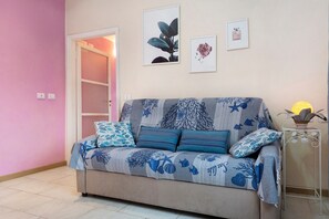 Een kamer met een bank, een klein tafeltje en wanddecoratie.