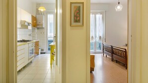 Una cocina con armarios blancos, una silla amarilla y un comedor con banco y cortinas.