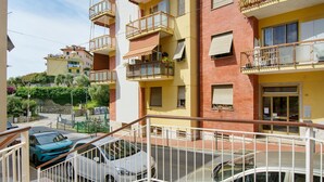 Un edificio residencial de varios pisos con balcones, una zona de estacionamiento cerrada y vista a la calle.
