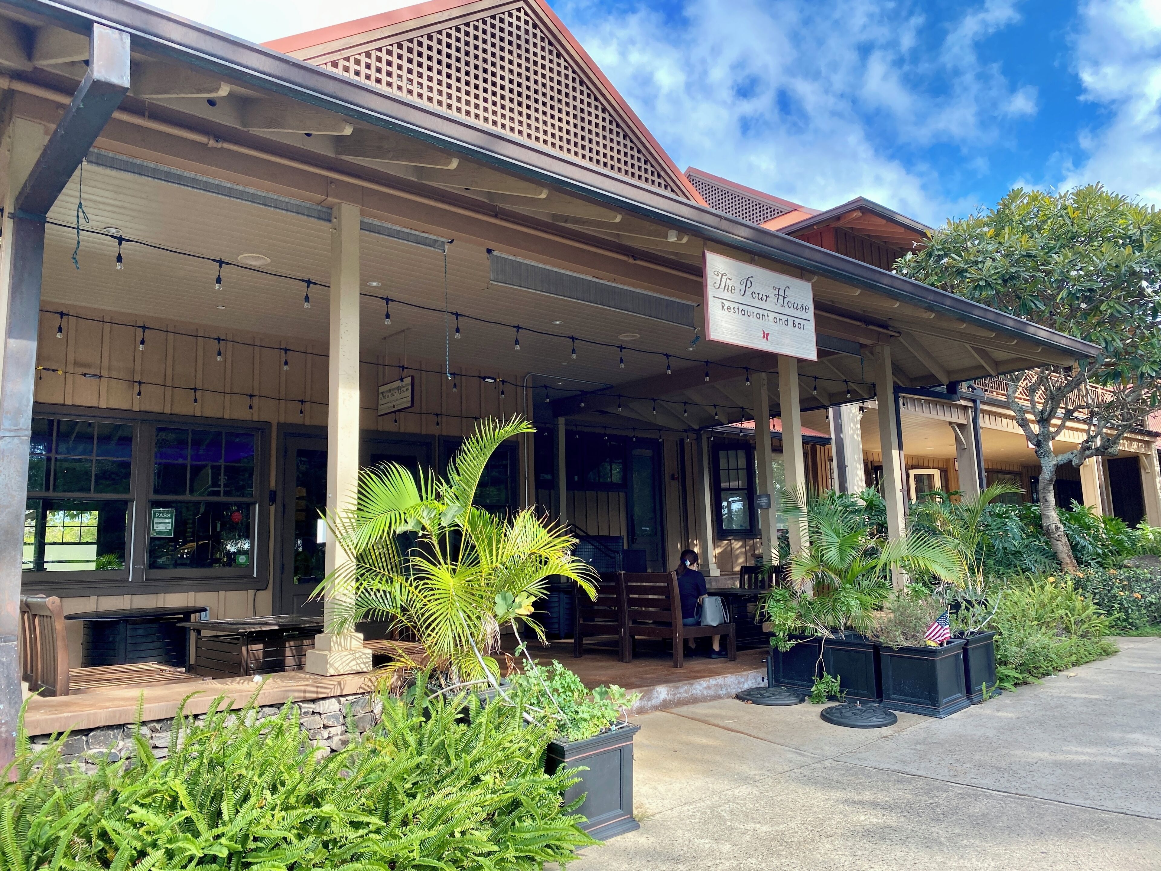 Dine at The Pour House Italian Kitchen & Wine Bar nearby, offering a cozy patio with string lights, tropical plants, and inviting outdoor seating.