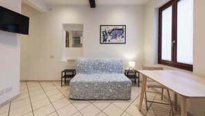 Una sala moderna con un sofá, una mesa de comedor y un televisor montado en la pared.