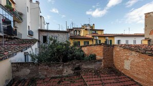 Un estrecho callejón con tejados de tejas de arcilla y paredes de ladrillo, rodeado de edificios con balcones y unidades de aire acondicionado.
