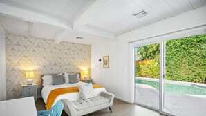 A bedroom with a bed, bedside tables, a chair, and a view of a swimming pool. - Hip & Spacious Contemporary Haven - A Ryson Property (Palm Springs)