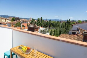 A balcony with a table, a bowl of fruit, and a glass of wine. - San Frediano Designer Duplex (Firenze)