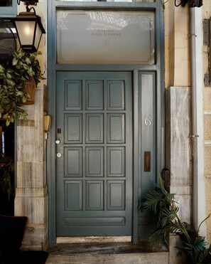 A dark green door with a grid pattern, a small plaque above it, and a potted plant to the right. - Luxurious Loft in Monastiraki (Athens)