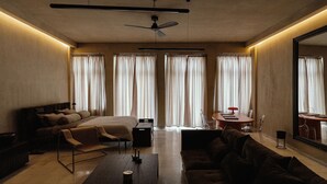 A modern hotel room with a bed, sofa, coffee table, and a dining area with a table and chairs. - Luxurious Loft in Monastiraki (Athens)