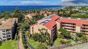 Un resort con varias construcciones, paneles solares en los techos y vista al océano.