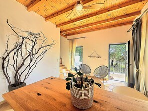 A wooden dining table with a woven basket containing plants, a ceiling fan, and a view of a balcony with a railing. - Villa 'Õku' with Sea View, Wi-Fi and Air Conditioning (Rincovo)