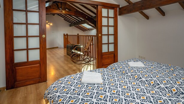 Ein Schlafzimmer mit Bett, einer Holztür mit Glasfeldern, einem Deckenventilator und Blick auf einen Balkon.