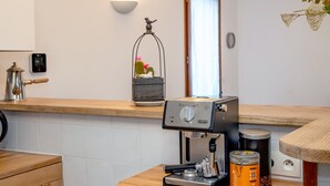 Eine Küche mit Kaffeemaschine, einer Kaffeedose und einem dekorativen Vogelkäfig.