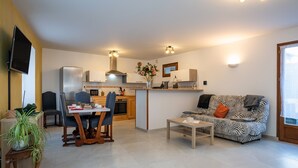 Ein modernes Wohnzimmer mit Sofa, Esstisch und Küchenzeile.