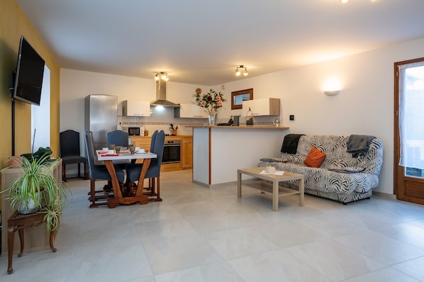 A modern living room with a sofa, dining table, and kitchen area.
