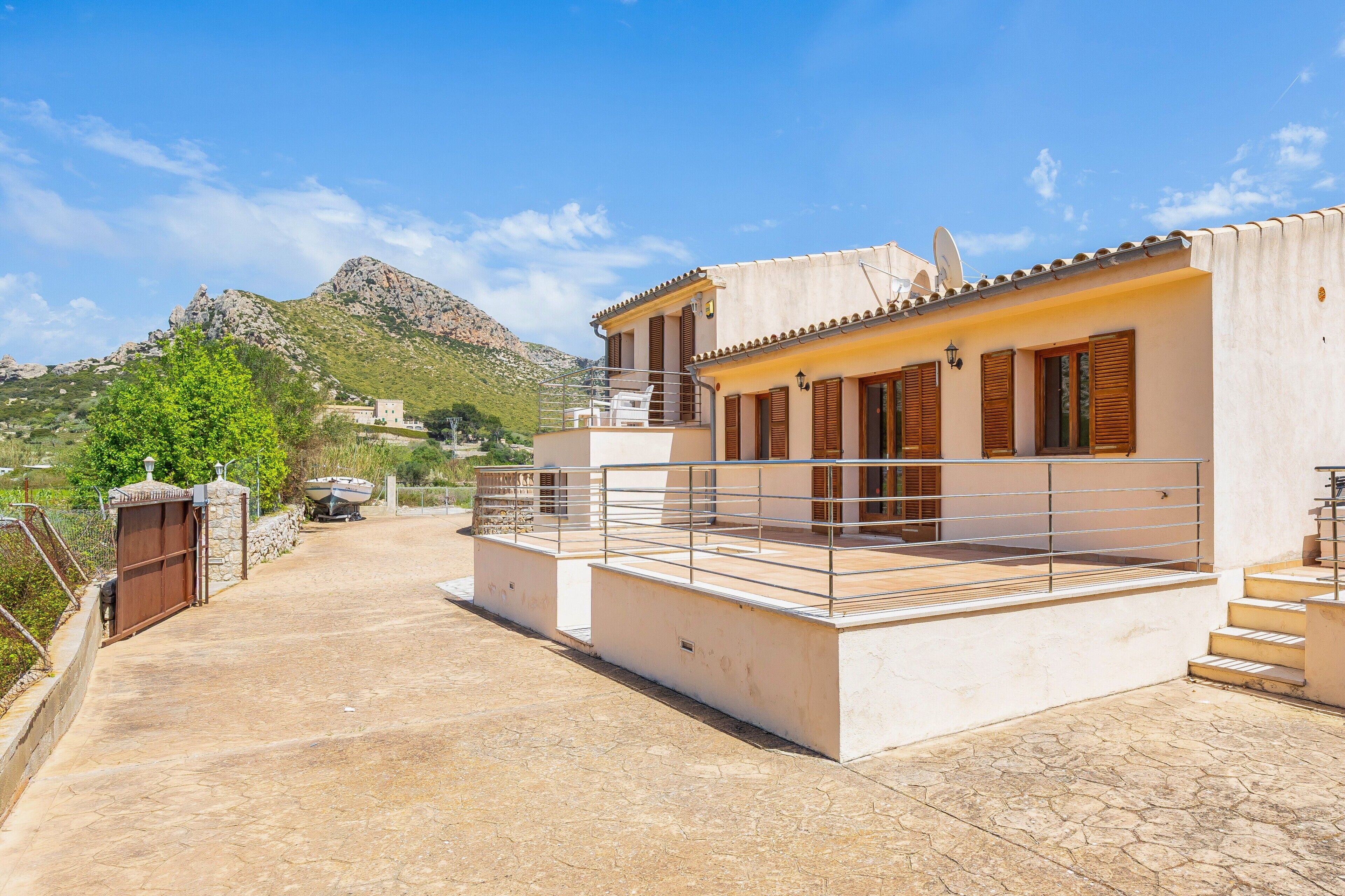 A modern building with a balcony, a stone pathway, and a mountainous backdrop.