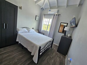 A bedroom with a bed, a wardrobe, a television, and an air conditioning unit. - Anne's Apartments  (Osbourn)