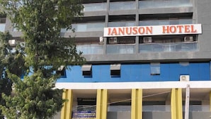 The Januson Hotel building facade with a sign, a Jeep parked in front, and potted plants at the entrance. - Januson Hotel (Gandhinagar)