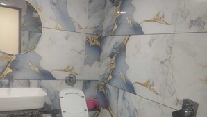 A bathroom with a toilet, sink, and a mirror. - Januson Hotel (Gandhinagar)