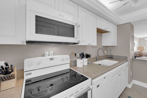 Una cocina moderna con muebles blancos, un microondas, una estufa y un lavamanos.