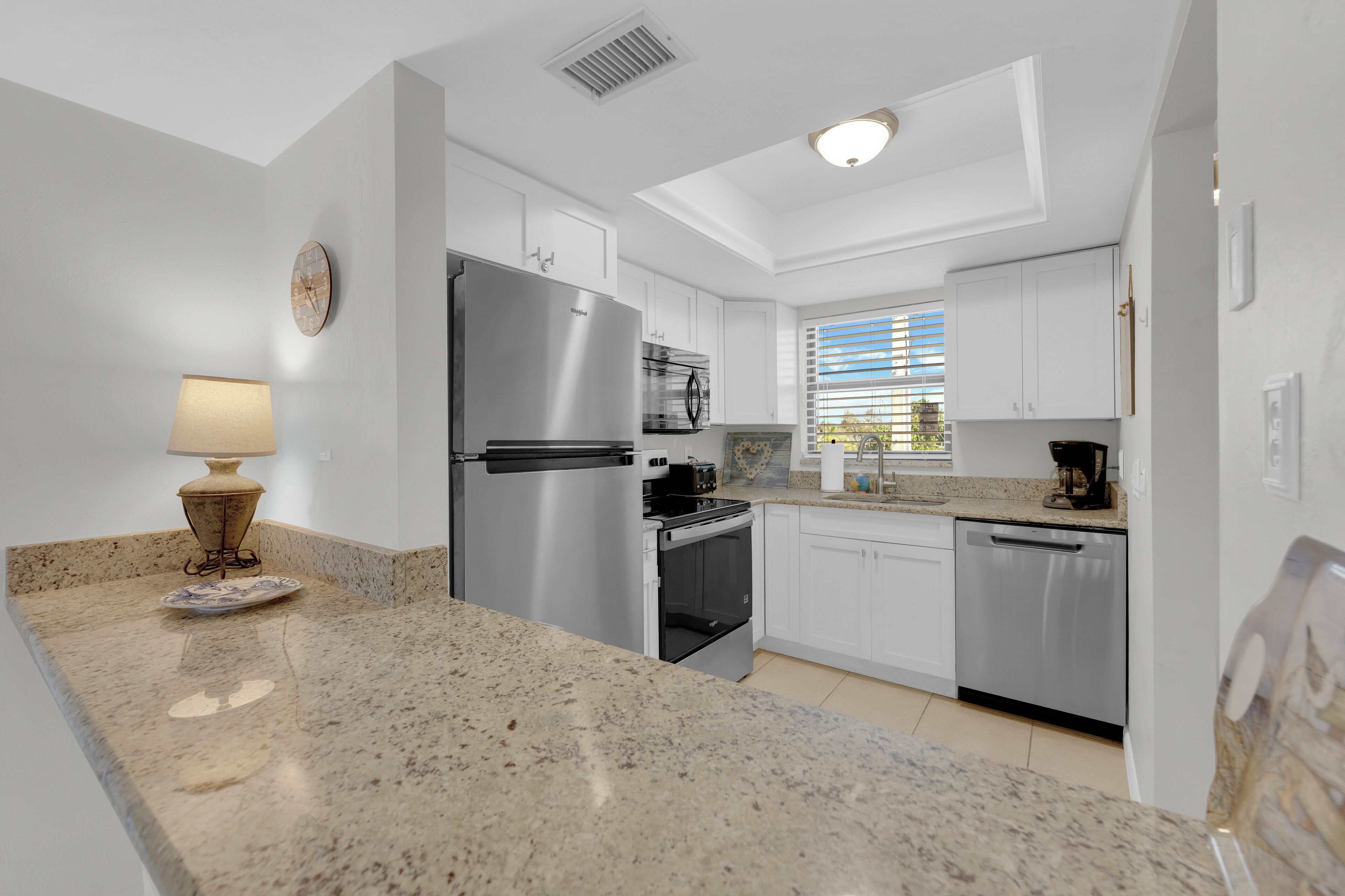 A modern kitchen with granite countertops, stainless steel appliances, and white cabinetry.