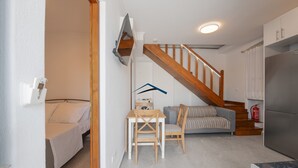 Un espacio habitable compacto con cocina, comedor y una escalera que sube a una habitación tipo loft.