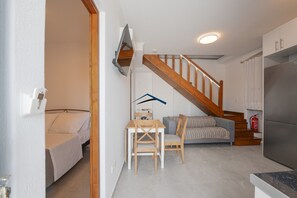A compact living space with a kitchen, dining area, and a staircase leading to a loft bedroom. - Villa Antika, very close to the shops and restaurants in Korissia, Kea. (Coressia)