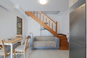 A compact living space with a wooden staircase, a sofa, a dining table, and a refrigerator. - Villa Antika, very close to the shops and restaurants in Korissia, Kea. (Coressia)