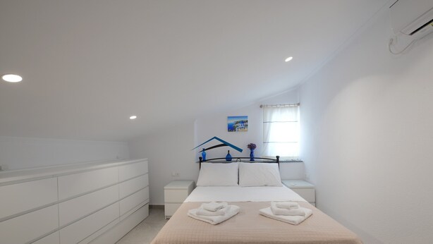 Un dormitorio con cama, mesita de noche, cómoda y ventana con cortinas.