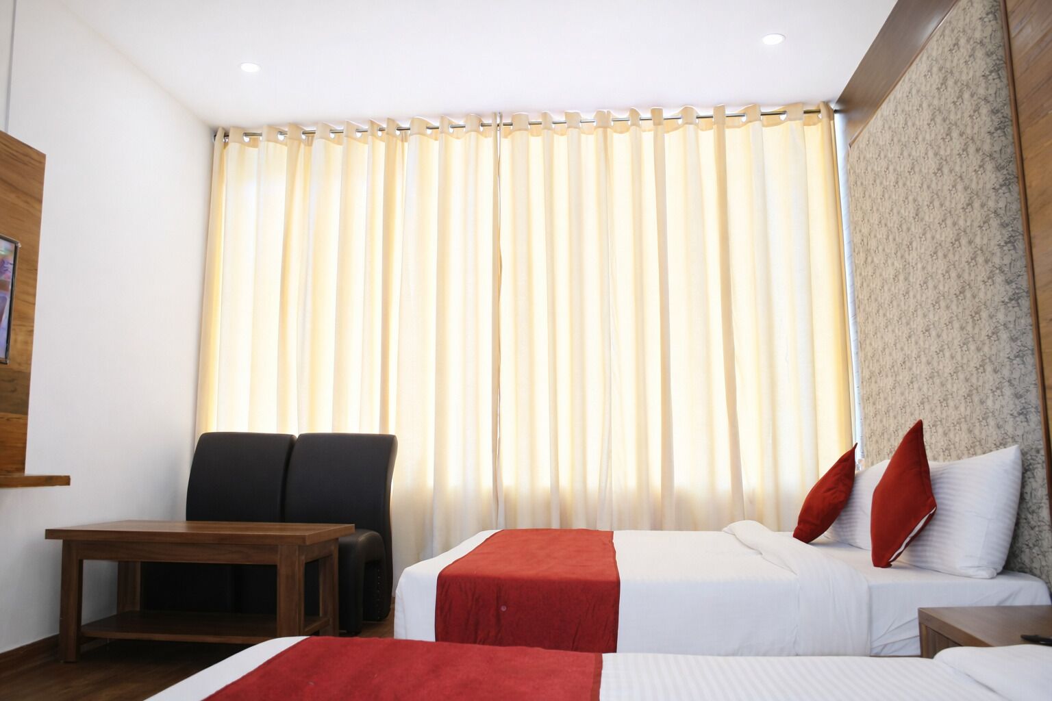 A hotel room with two beds, a wooden table, and a chair.