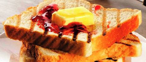 Deux tranches de pain grillé, beurrées et garnies de confiture, sur une assiette blanche.