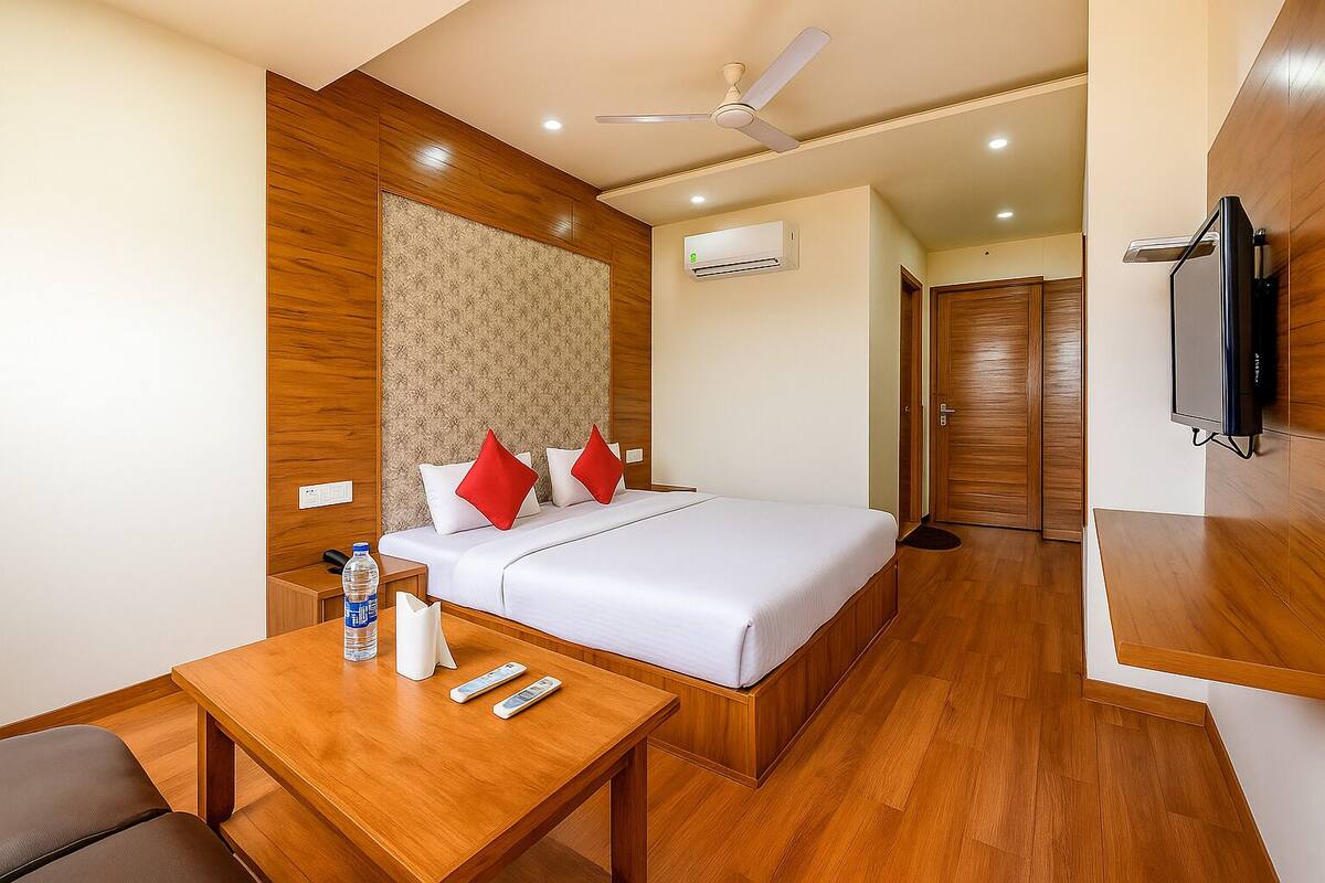 A hotel room with a bed, a wooden desk, a television, and a ceiling fan.