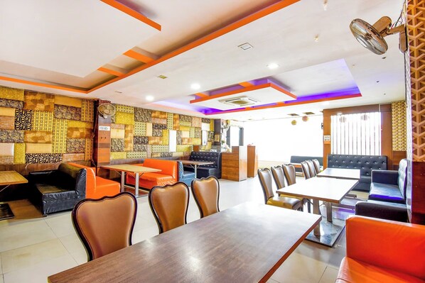 A restaurant with a modern interior, featuring a mix of seating options including tables and booths, and a patterned wall design. - Hotel Black Diamond (Zirakpur)